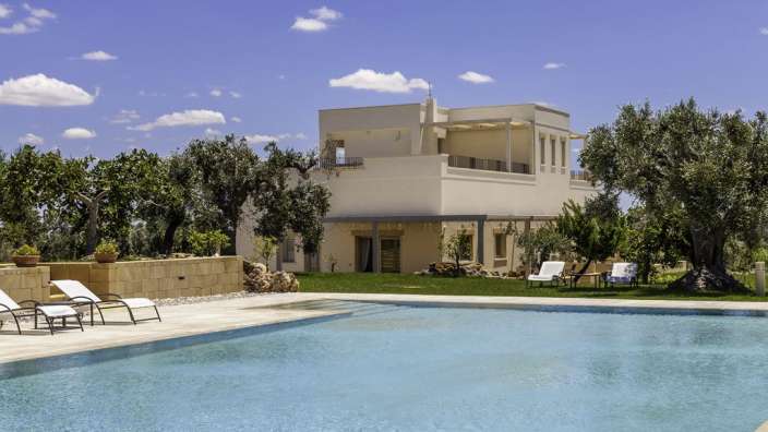 Ein großes weißes Haus mit einem Pool im Vordergrund