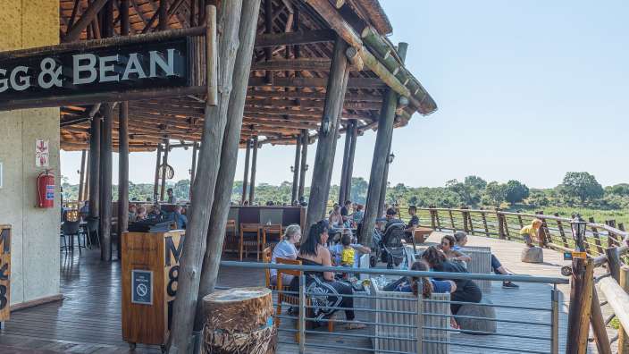 Eine Gruppe von Menschen sitzt an einem Tisch unter einem Schild mit der Aufschrift gg & bean