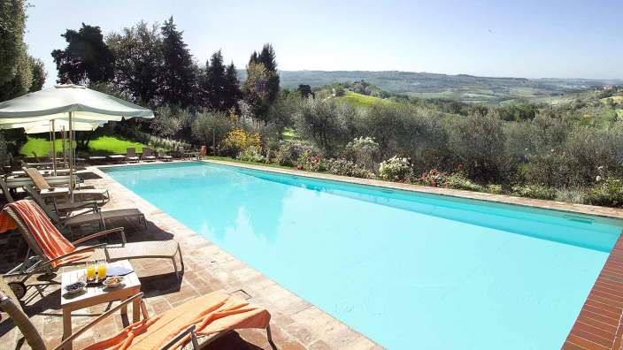 Ein großer Swimmingpool mit Liegestühlen und Sonnenschirmen umgeben