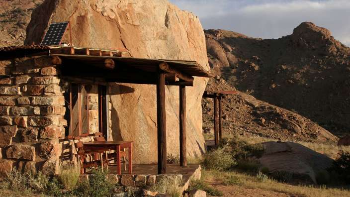 Ein Steingebäude mit einem Tisch und Stühlen auf der Veranda
