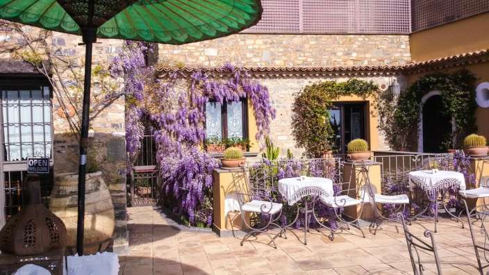 Ein grüner Regenschirm steht auf einem patio neben einem tisch und stühlen