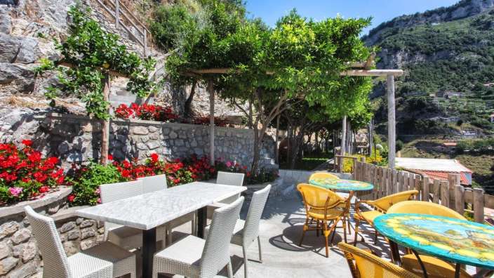 Eine Terrasse mit Tischen und Stühlen und einem Baum im Hintergrund