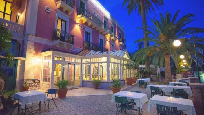 Ein Restaurant mit Tisch und Stühlen vor einem rosa Gebäude