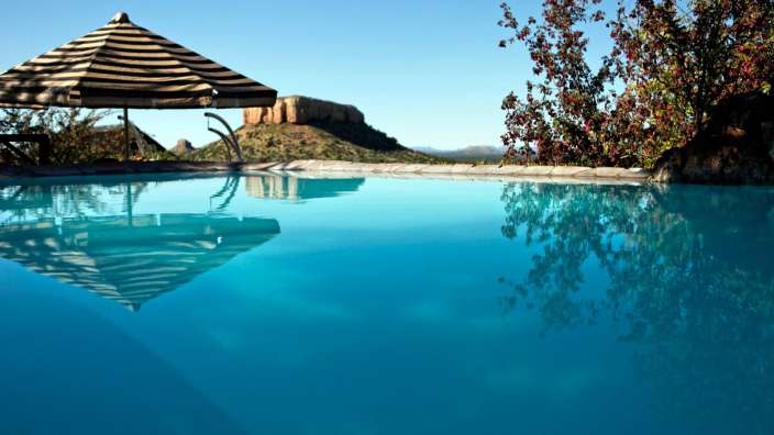 Ein Swimmingpool mit einem Regenschirm und einem Berg im Hintergrund