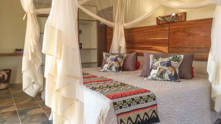 Ein Bett mit weißen Vorhängen und Kissen mit Elefantenmotiven