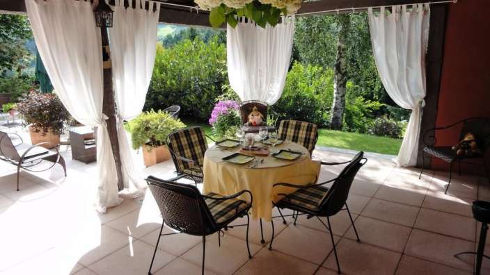 Ein Tisch und Stühle auf einer Terrasse mit weißen Vorhängen
