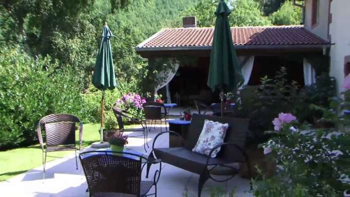 Eine Terrasse mit einem Tisch und Stühlen und einem grünen Regenschirm