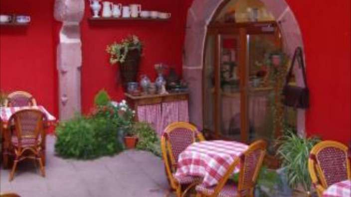 Eine Terrasse mit Tischen und Stühlen vor einem roten Gebäude .