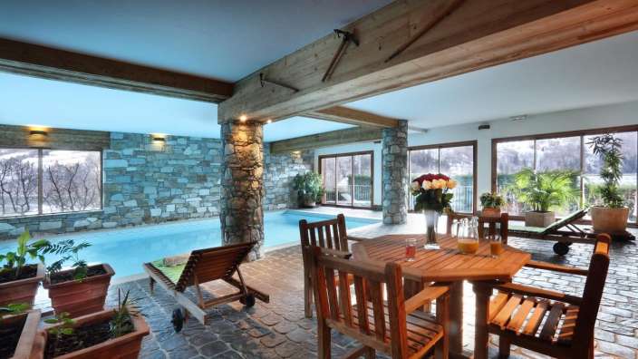 Ein Wohnzimmer mit einem Tisch und Stühlen neben einem Swimmingpool