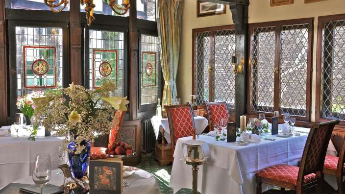 Ein Speisesaal mit einem Tisch und Stühlen und vielen Fenstern