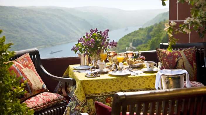 Ein Tisch mit einem gelben Tischtuch auf einem Balkon mit Blick auf einen Fluss
