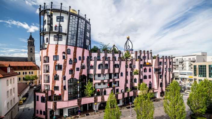 Ein rosa und weißes Gebäude mit einem weißen Gebäude dahinter