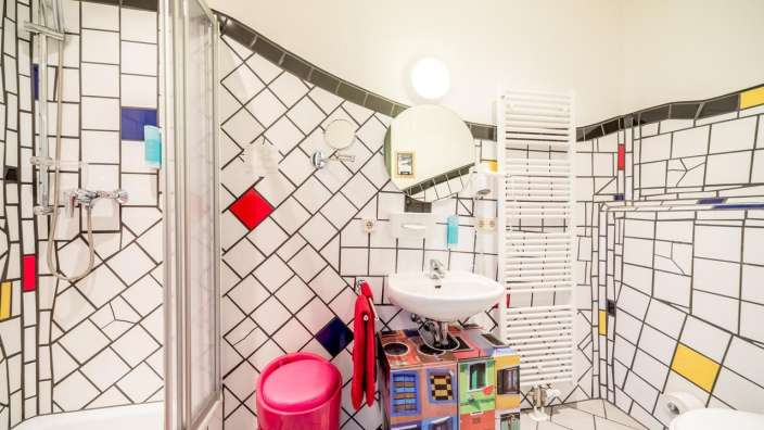Ein Badezimmer mit bunten Fliesen und einem rosa Eimer