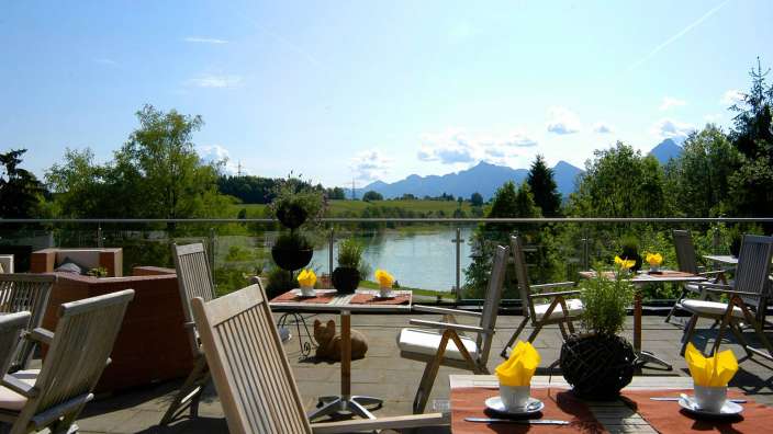 Tische und Stühle auf einem Balkon mit Blick auf einen See
