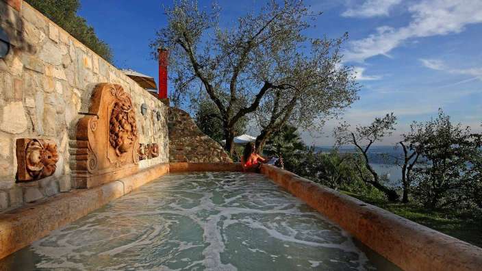 Eine Frau sitzt in einem Pool mit einem Löwenkopf darauf