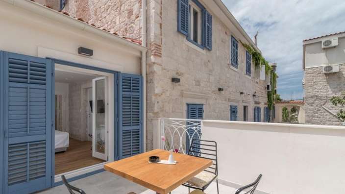 Ein Tisch und Stühle auf einem Balkon mit blauen Fensterläden