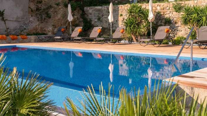 Liegestühle und Sonnenschirme umgeben einen großen Swimmingpool