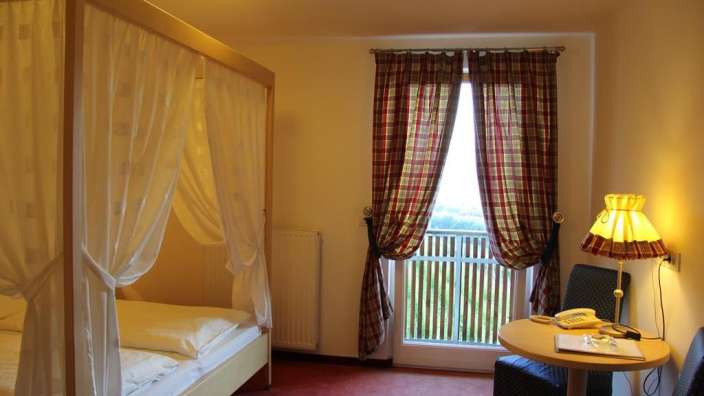 Ein Zimmer mit einem Himmelbett und einem Tisch