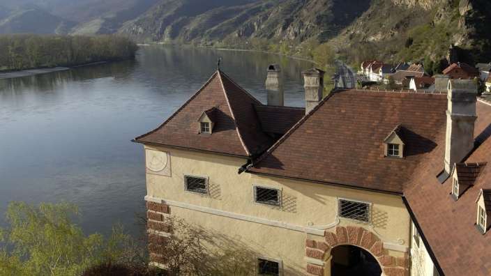 Ein Gebäude neben einem Fluss und einem Berg