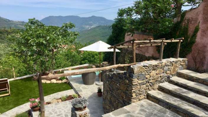 Ein weißer Regenschirm sitzt auf einer Steinterrasse mit Blick auf die Berge