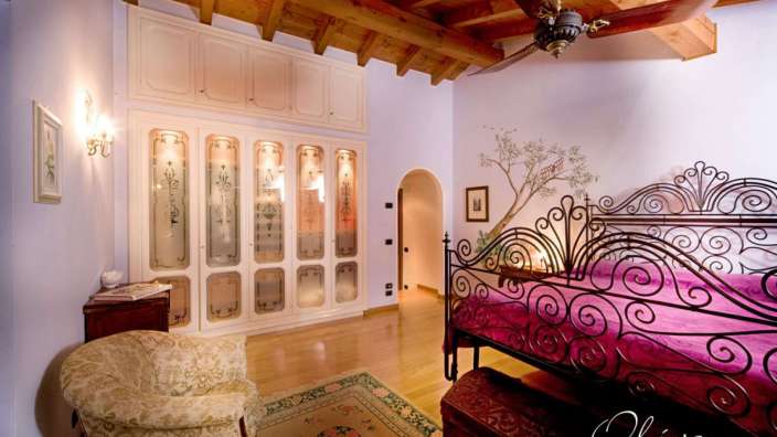 Ein Schlafzimmer mit einem schmiedeeisernen Bett und der Aufschrift olivo