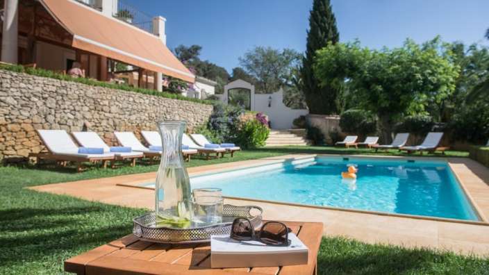 Ein Tisch mit einem Buch und einer Flasche Wasser neben einem Swimmingpool