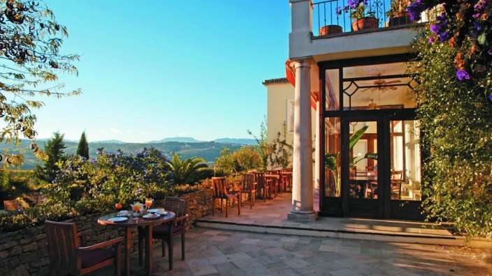 Eine Terrasse mit einem Tisch und Stühlen vor einem Haus