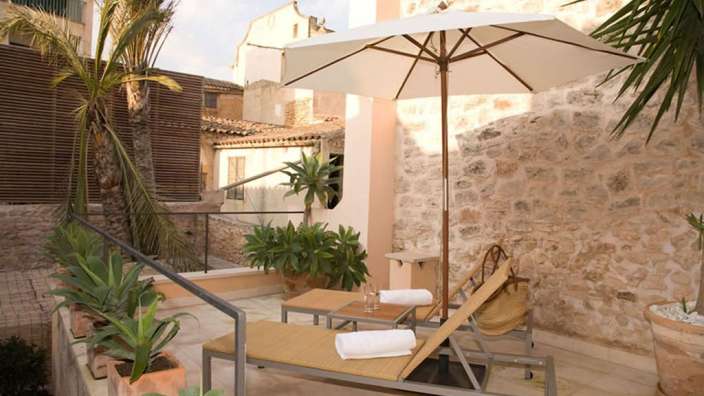 Eine Terrasse mit Liegestühlen und einem weißen Regenschirm