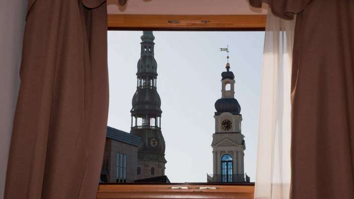 Ein Fenster mit braunen Vorhängen und einem Uhrturm dahinter