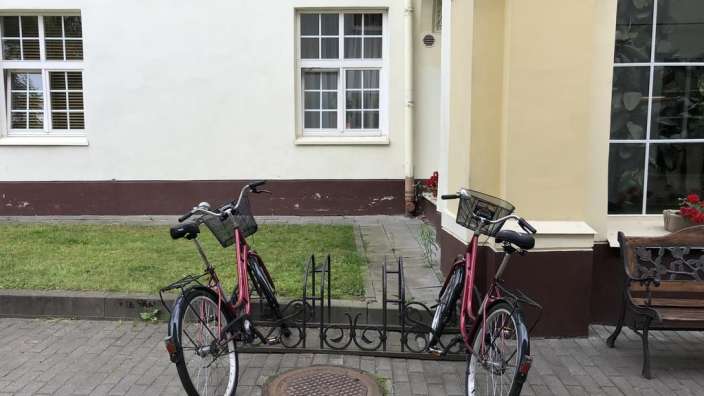 Zwei Fahrräder stehen auf einem Fahrradhalter vor einem Gebäude