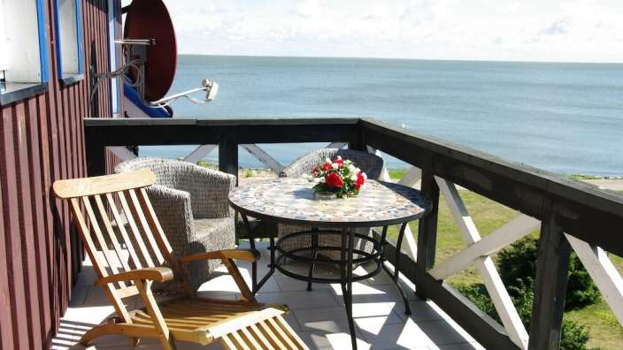 Ein Balkon mit Tisch und Stühlen mit Blick auf das Meer