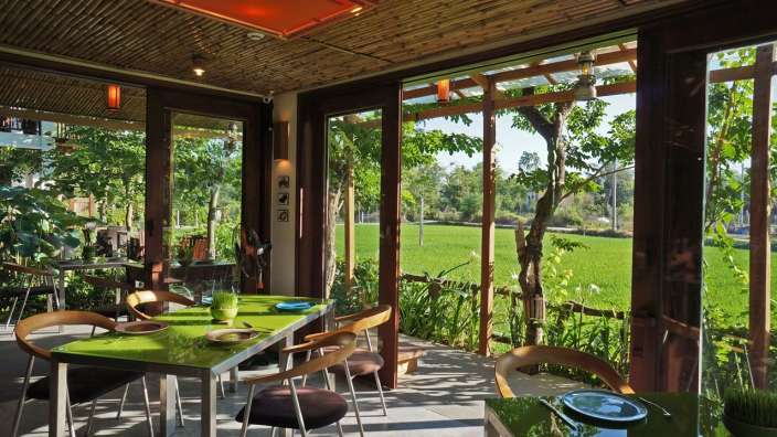 Tische und Stühle in einem Restaurant mit Blick auf einen Reisfeld