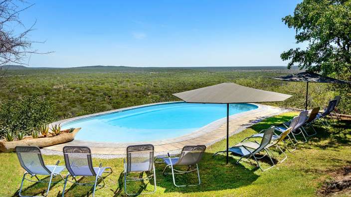 Liegestühle und Sonnenschirme umgeben einen großen Swimmingpool