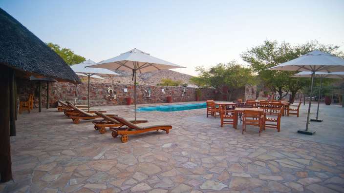 Liegestühle und Sonnenschirme stehen neben einem Pool