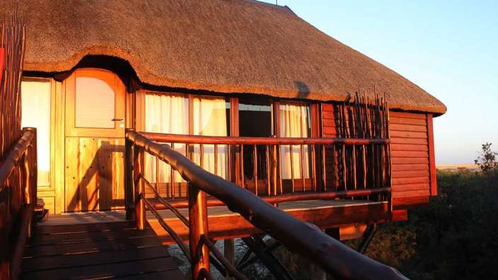Ein rotes Holzhaus mit Strohdach und einem Holzdeck