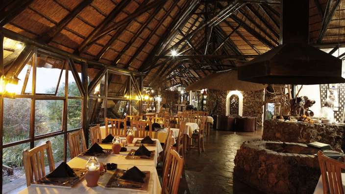 Ein Esszimmer mit Strohdach und vielen Tischen und Stühlen