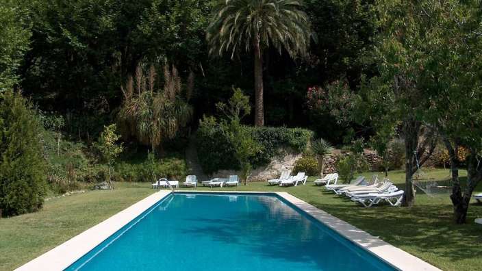 Ein großer Swimmingpool umgeben von Liegestühlen und Bäumen