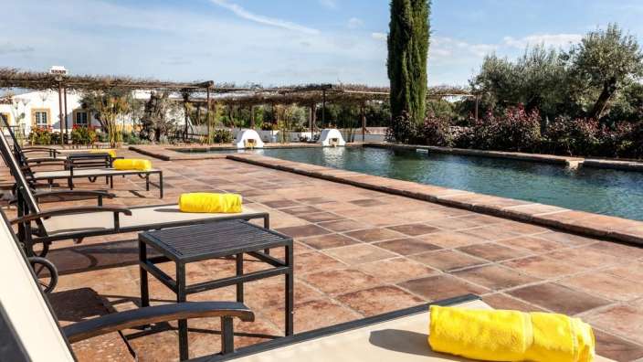 Liegestühle mit gelben Handtüchern neben einem Pool