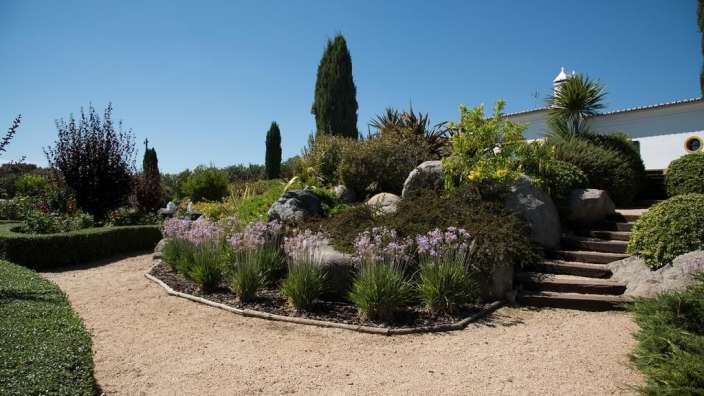 Ein Garten mit Treppen und Blumen und einem weißen Gebäude im Hintergrund