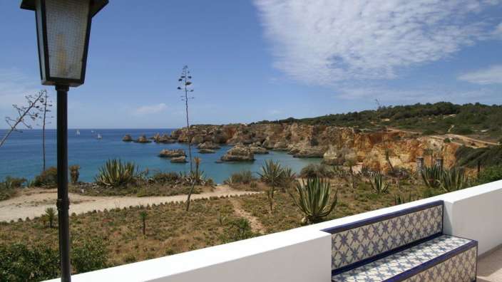 Eine Bank mit blauen und weißen Fliesen sitzt auf einem Balkon mit Blick auf den Ozean