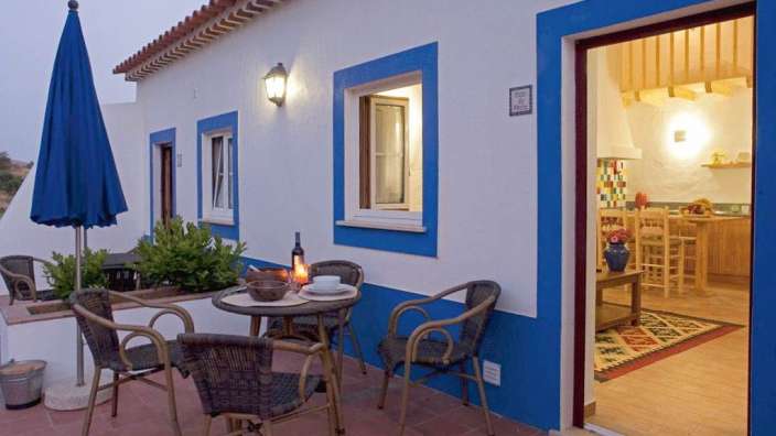 Ein blau-weißes Haus mit einem Tisch und Stühlen davor