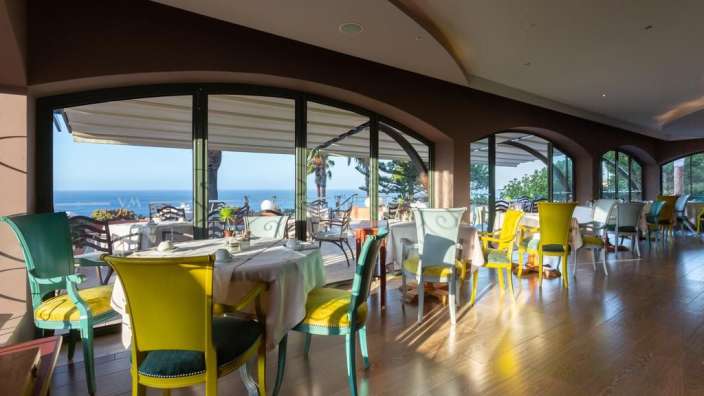 Ein Restaurant mit bunten Stühlen und Tischen mit Blick auf das Meer