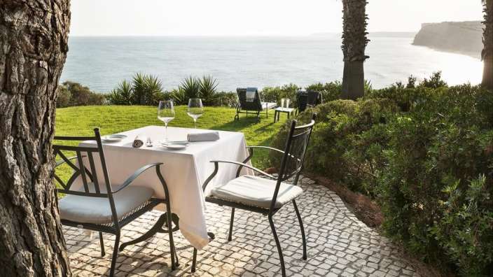 Ein Tisch und Stühle stehen auf einer Terrasse mit Blick auf das Meer