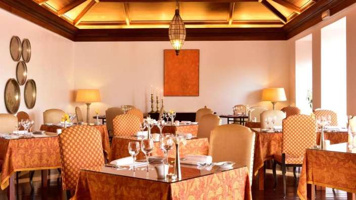 Ein Esszimmer mit Tischen und Stühlen und einem Gemälde an der Wand