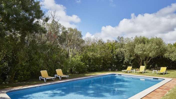 Ein großer Swimmingpool umgeben von gelben Stühlen und Bäumen