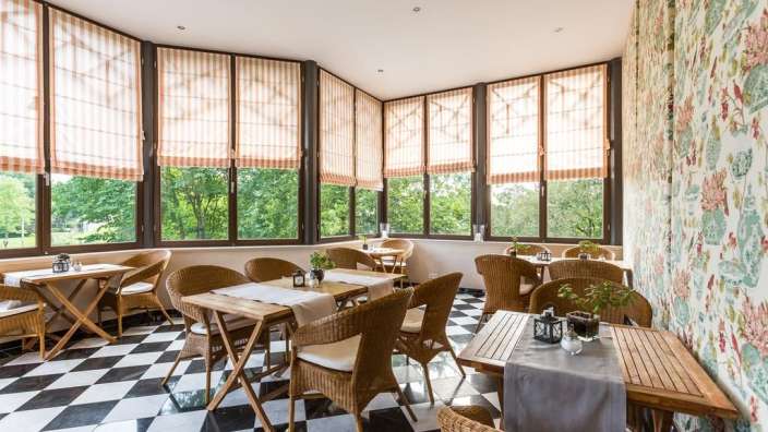 Tische und Stühle in einem Raum mit vielen Fenstern