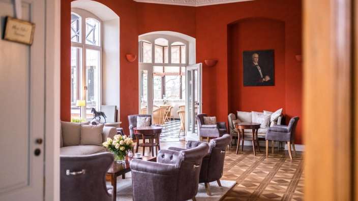 Ein Wohnzimmer mit roten Wänden und einem Porträt eines Mannes an der Wand