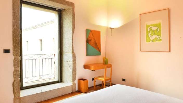 Ein Schlafzimmer mit einem Bett, einem Schreibtisch und einem Gemälde an der Wand