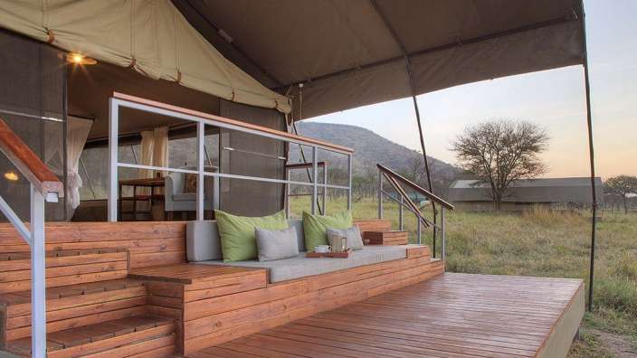 Ein Holzdeck neben einem Zelt mit grünen Kissen