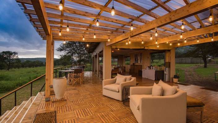 Ein Holzdeck mit Stühlen und Tischen unter einer transparenten Decke